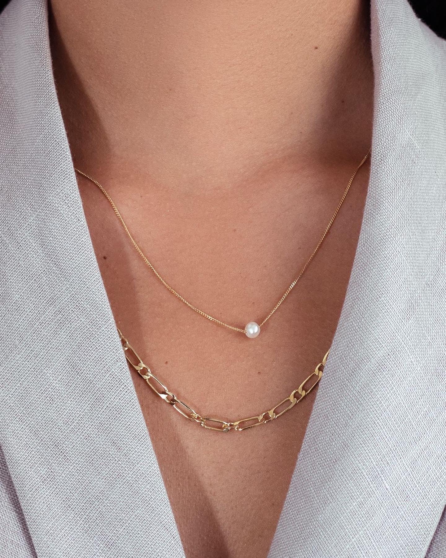 This dainty necklace features an A-grade freshwater pearl gracefully strung on a sterling silver curb chain, creating a classic and timeless look.. model layers her necklaces