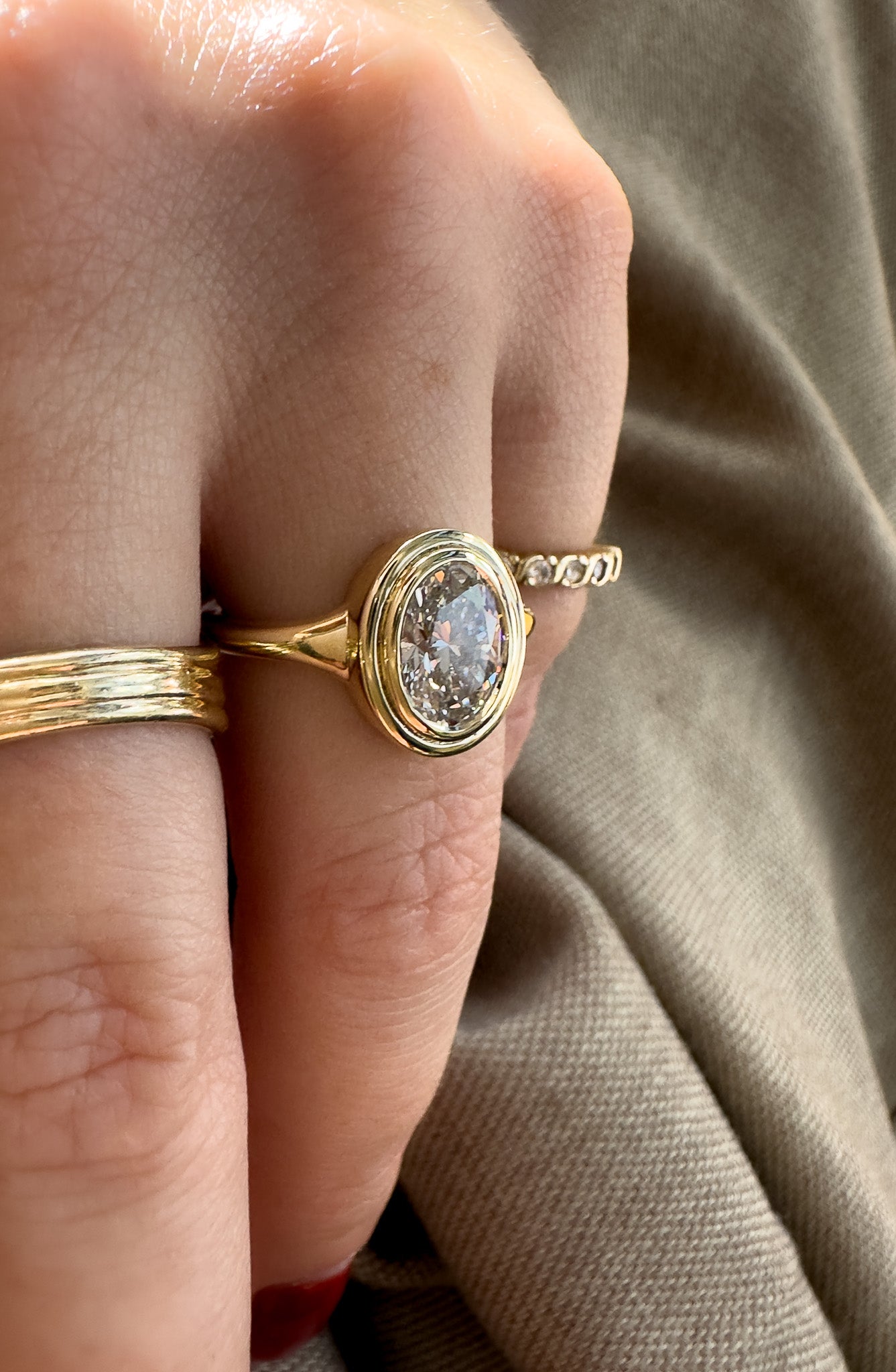 Gold ring with a diamond on a finger against a neutral background