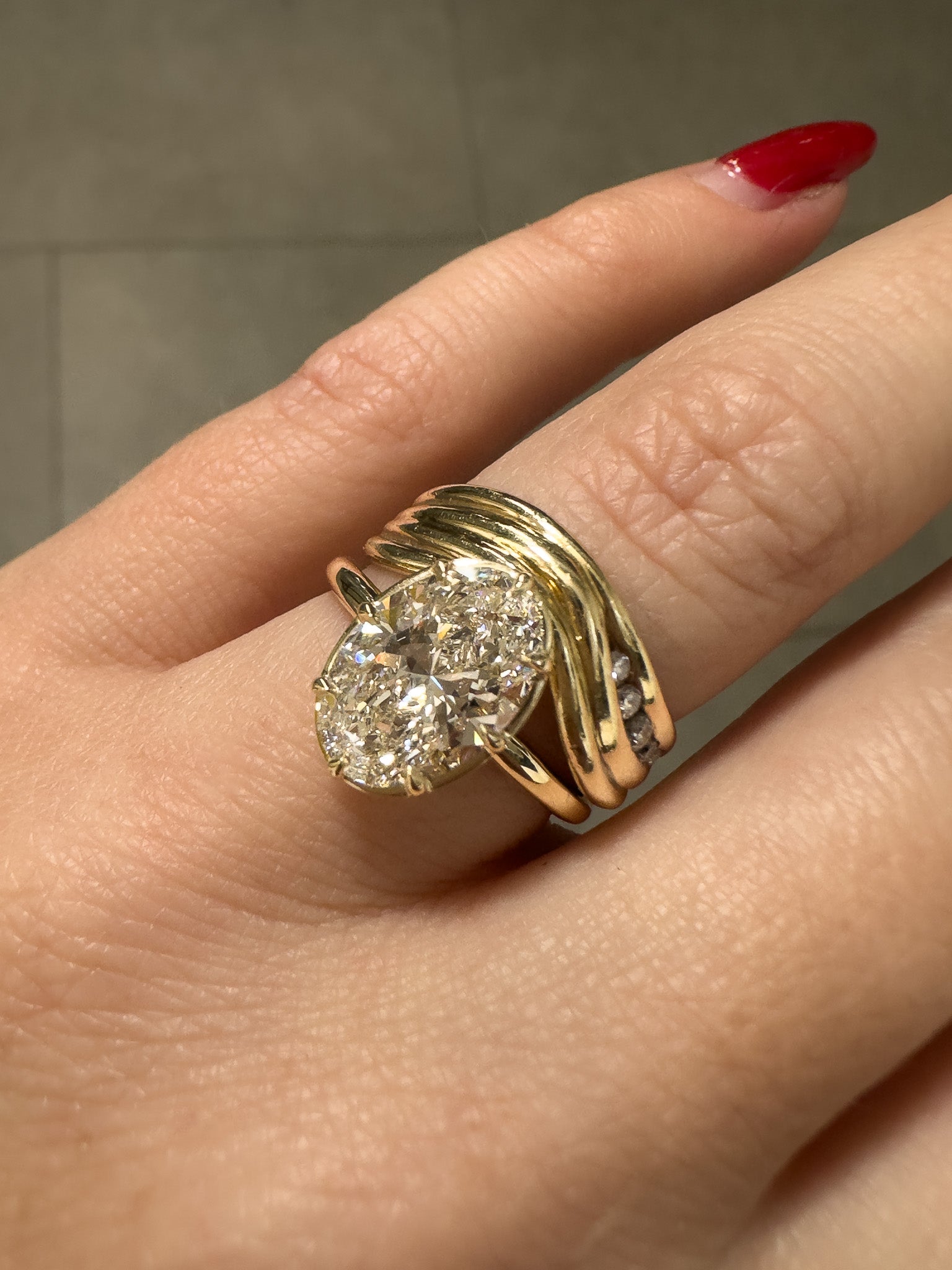 Gold ring with a diamond on a finger against a neutral background