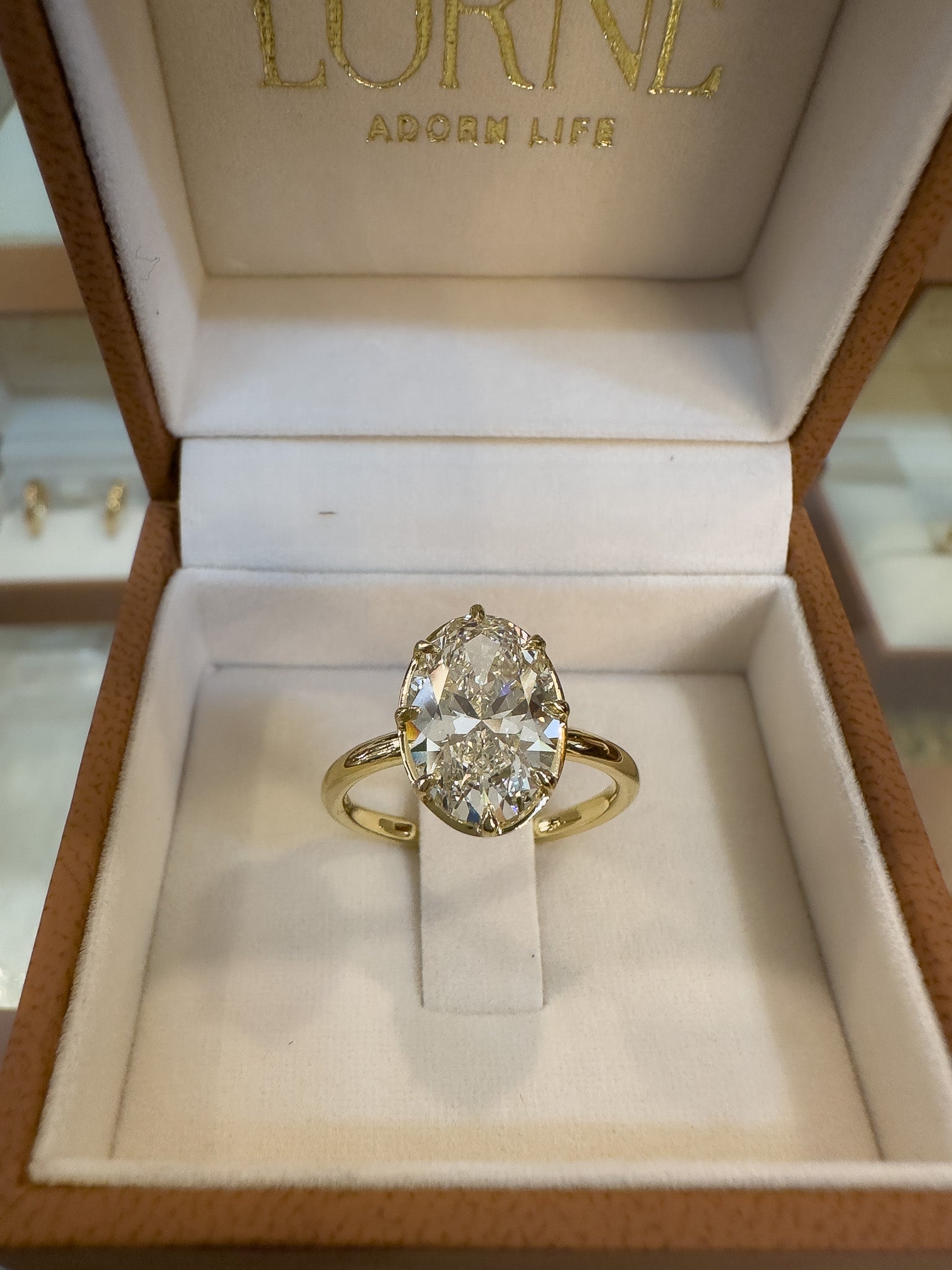 Gold ring with a diamond in a jewelry box labeled 'Lorne'.