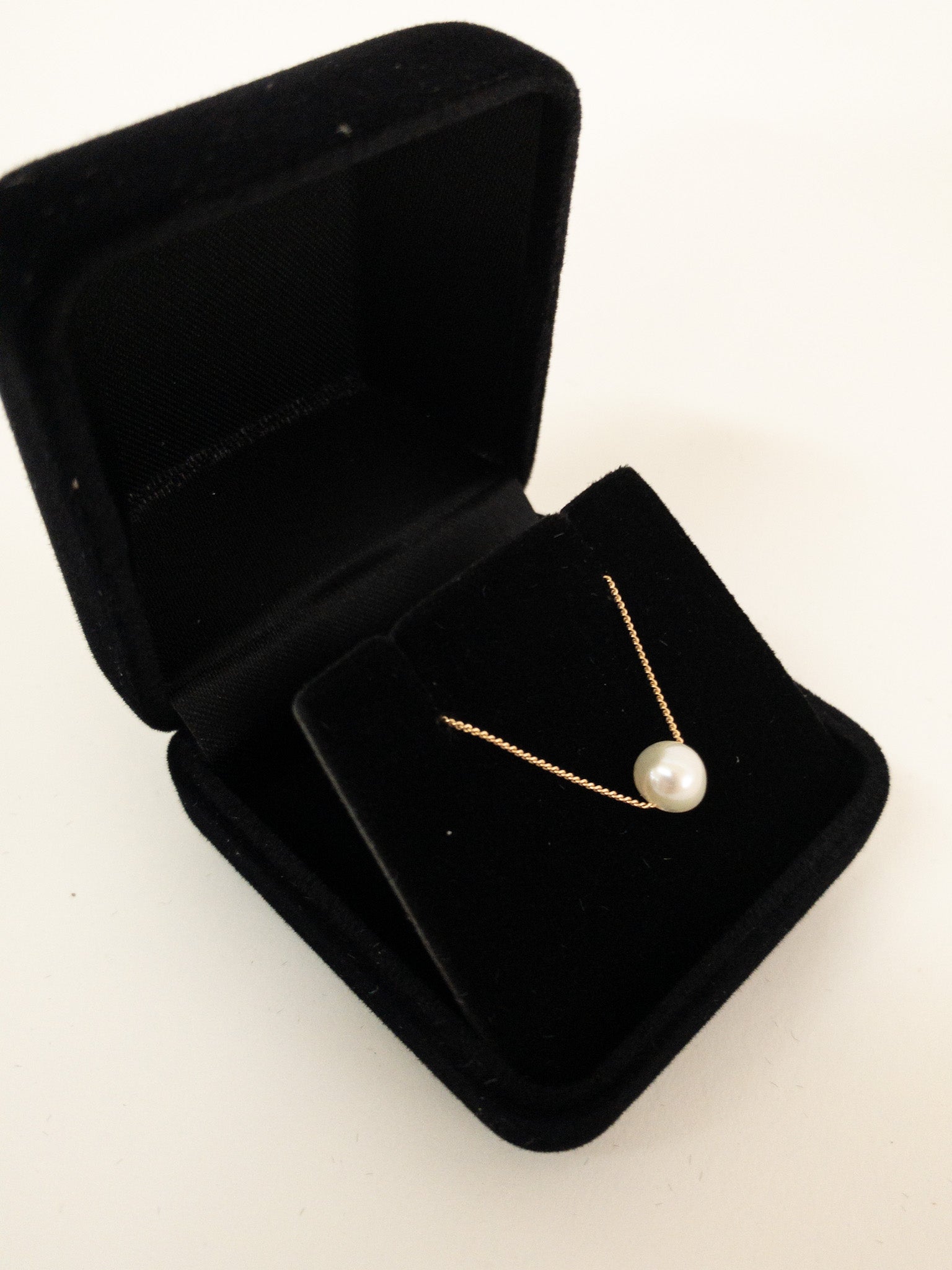 This dainty necklace features an A-grade freshwater pearl gracefully strung on a sterling silver curb chain, creating a classic and timeless look. necklace displayed inn velvet pendant box
