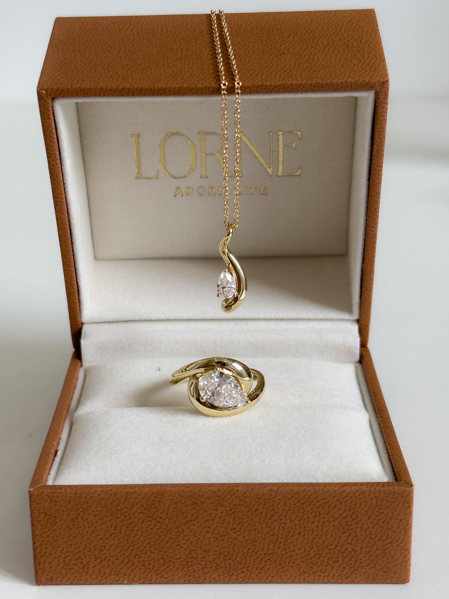 Gold ring and necklace set in a brown jewelry box with 'Lorne' branding