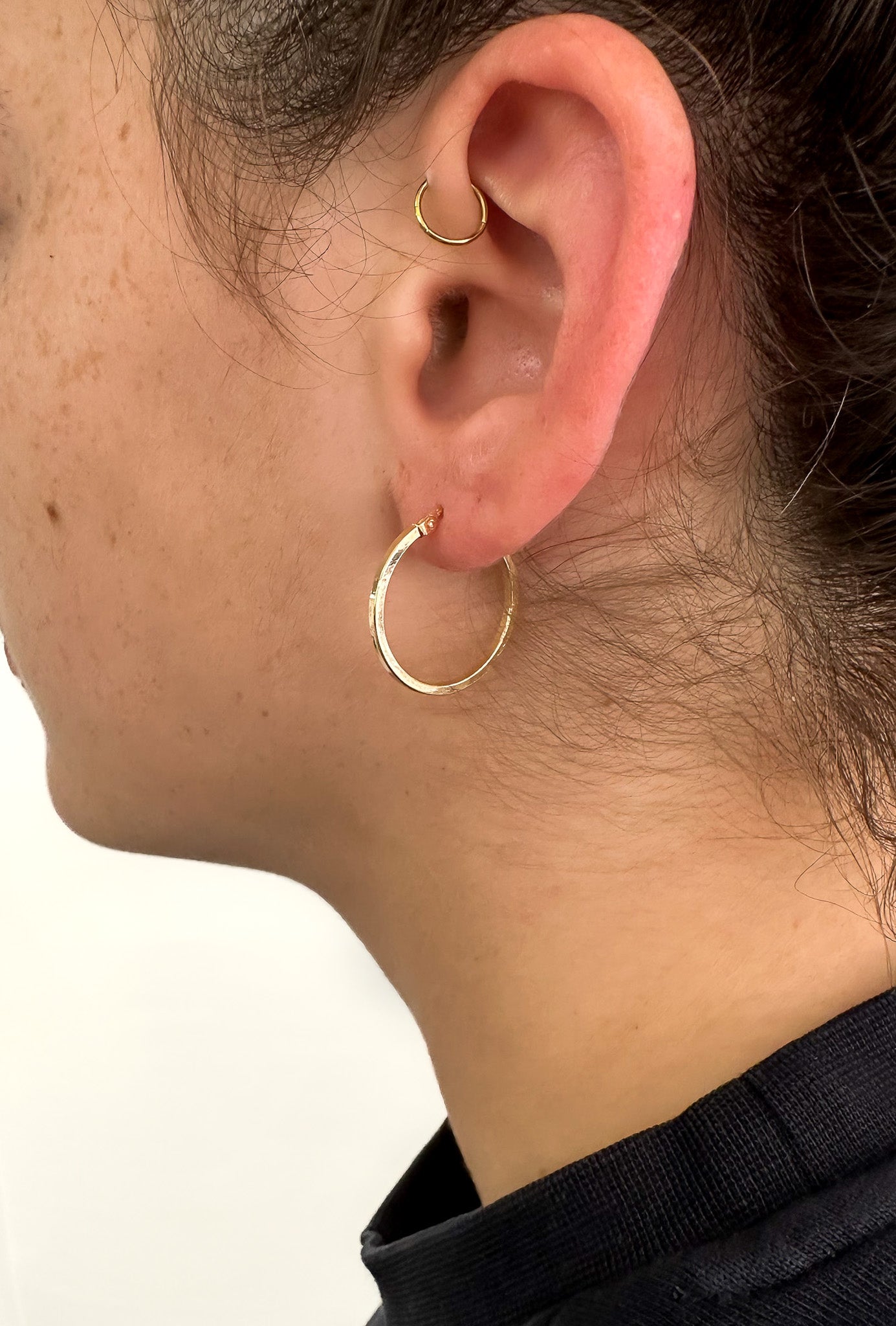 model wearsLORNE 9ct Yellow Gold 20mm Hoop Earring—a minimalist's dream of clean lines and reflective surfaces.
