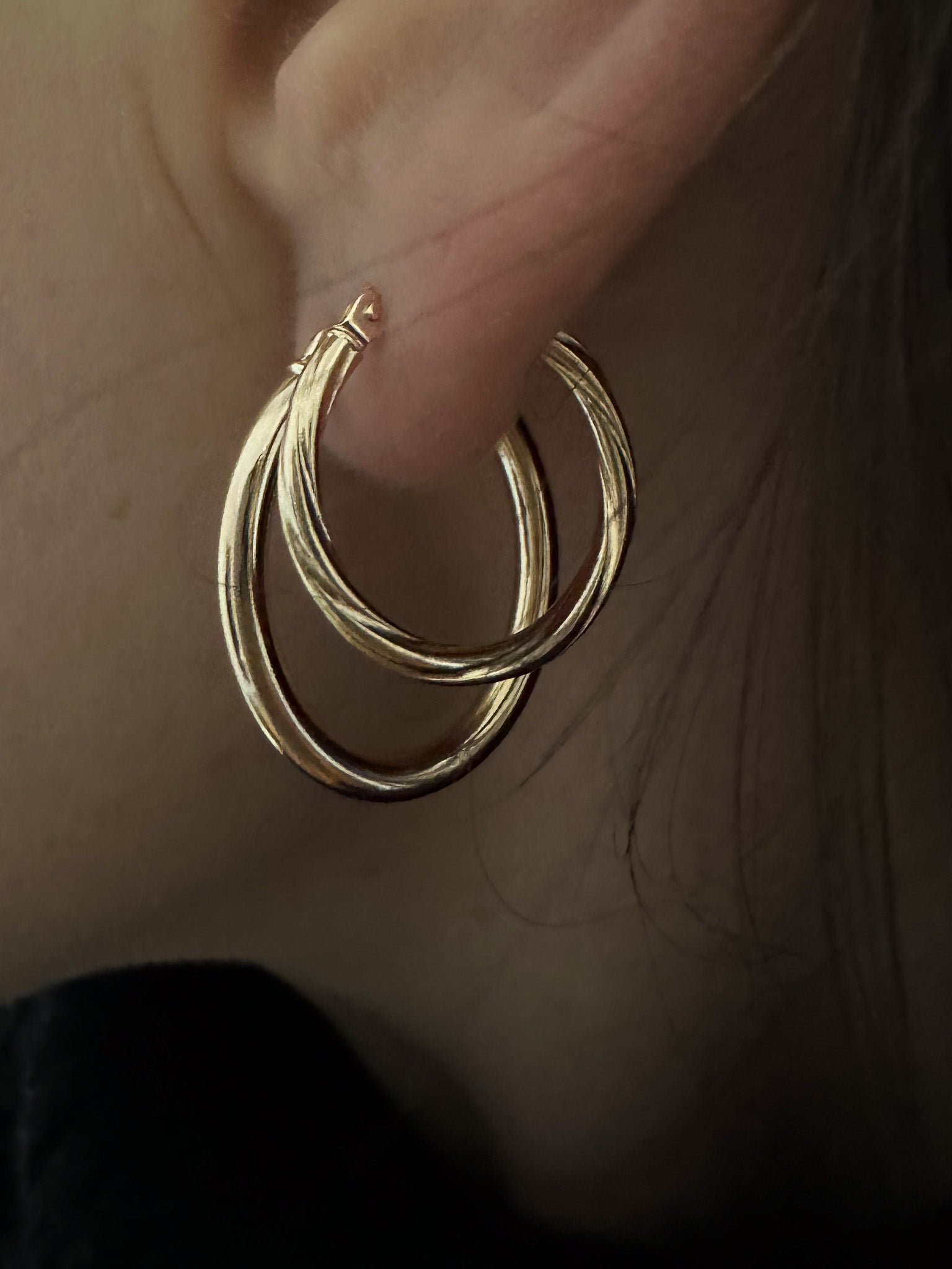 model stacks and layers her gold hoop earrings with her multiple ear piercings