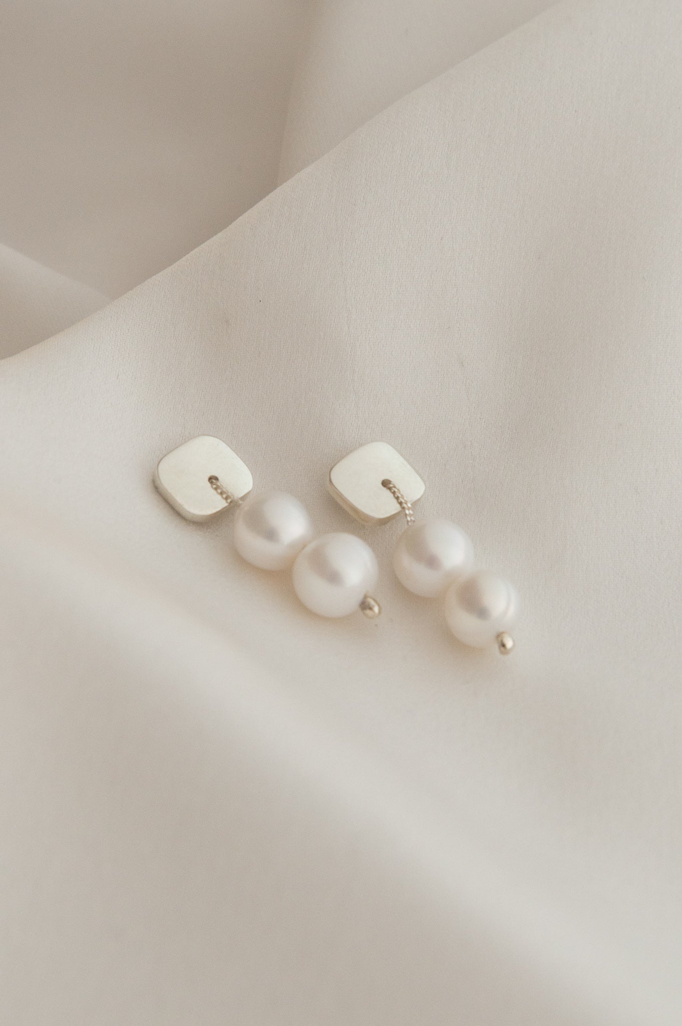 Dangling pearl earrings.  This pair features two 8mm lustrous, high-grade freshwater pearls, each strung on a durable sterling silver chain and securely connected to a sturdy sterling silver base.