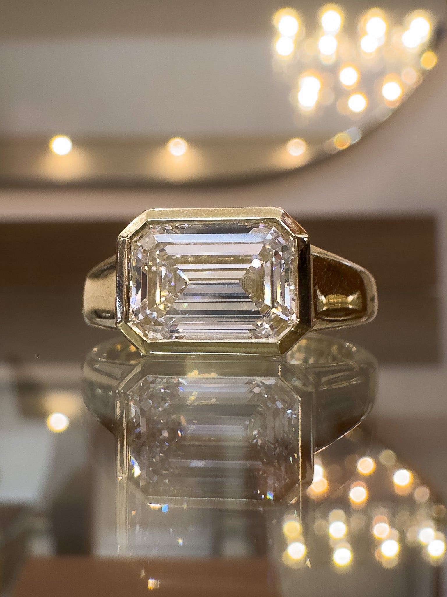 Gold ring with a large diamond on a reflective surface