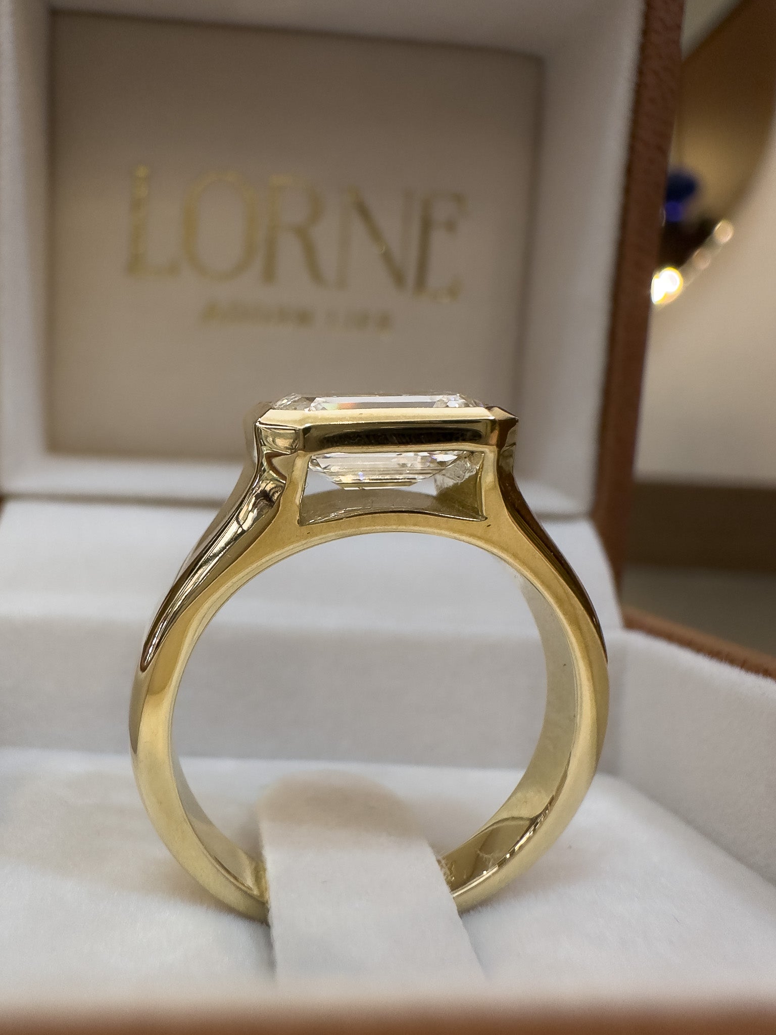 Gold ring with a diamond in a box with 'LORNE' branding.