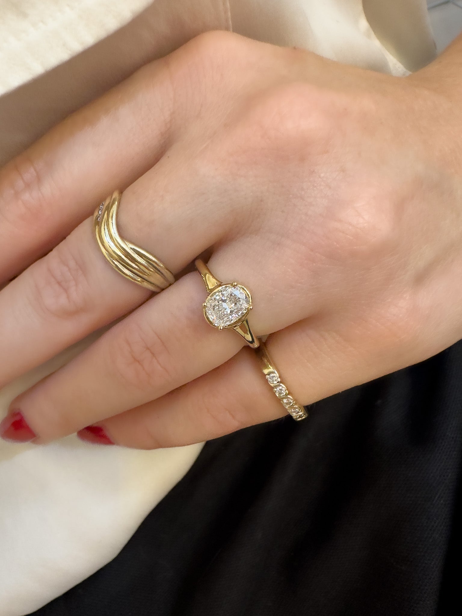 Close-up of a hand wearing a gold ring with a diamond on a neutral background