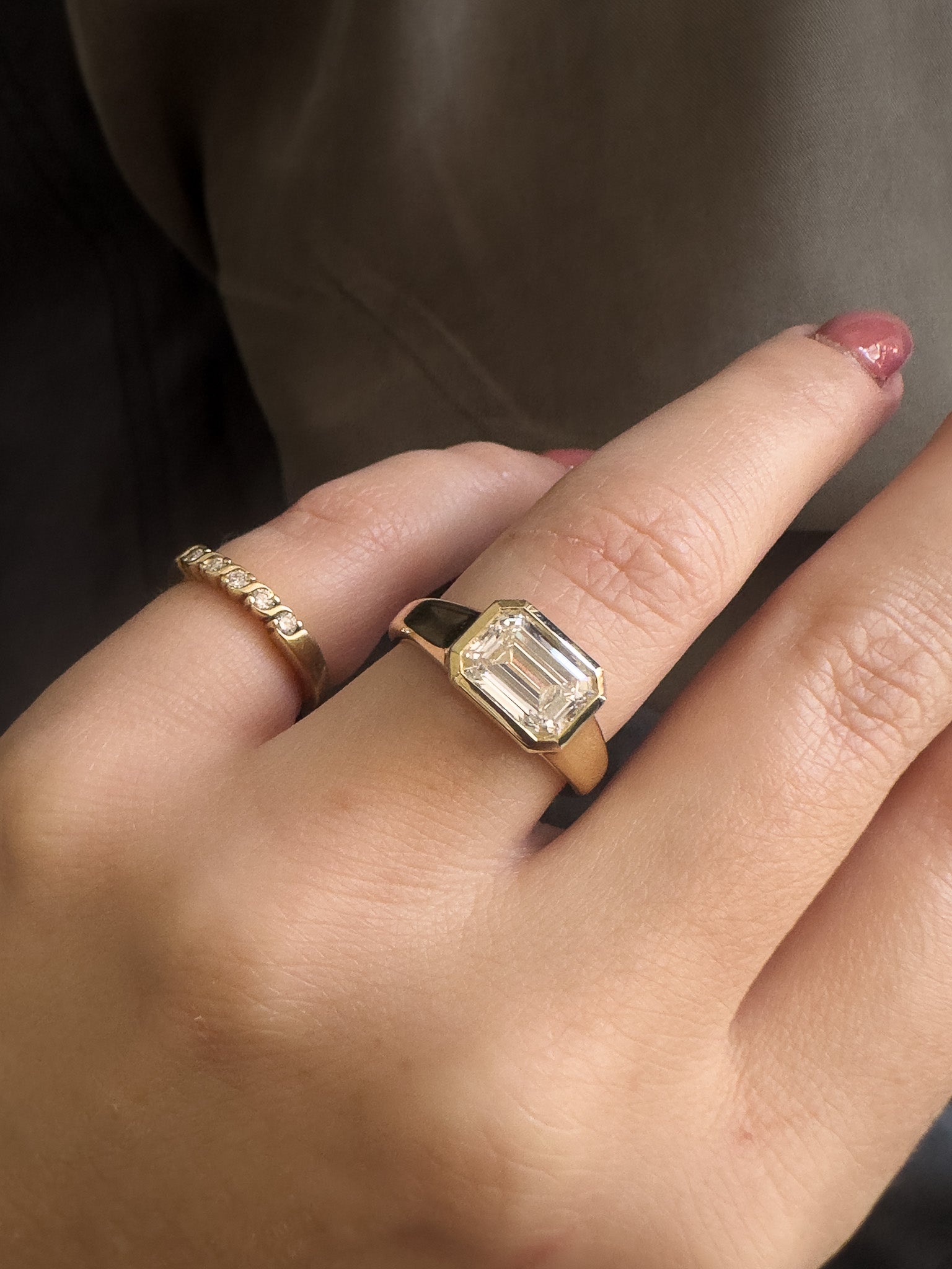Close-up of a hand wearing two gold rings with a dark background