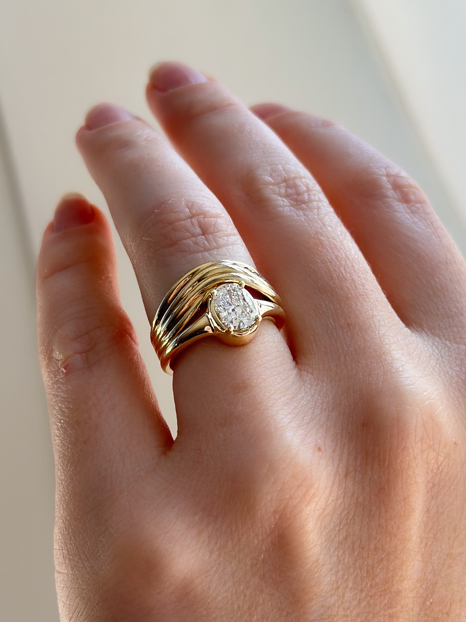 Gold ring with a diamond on a hand against a neutral background