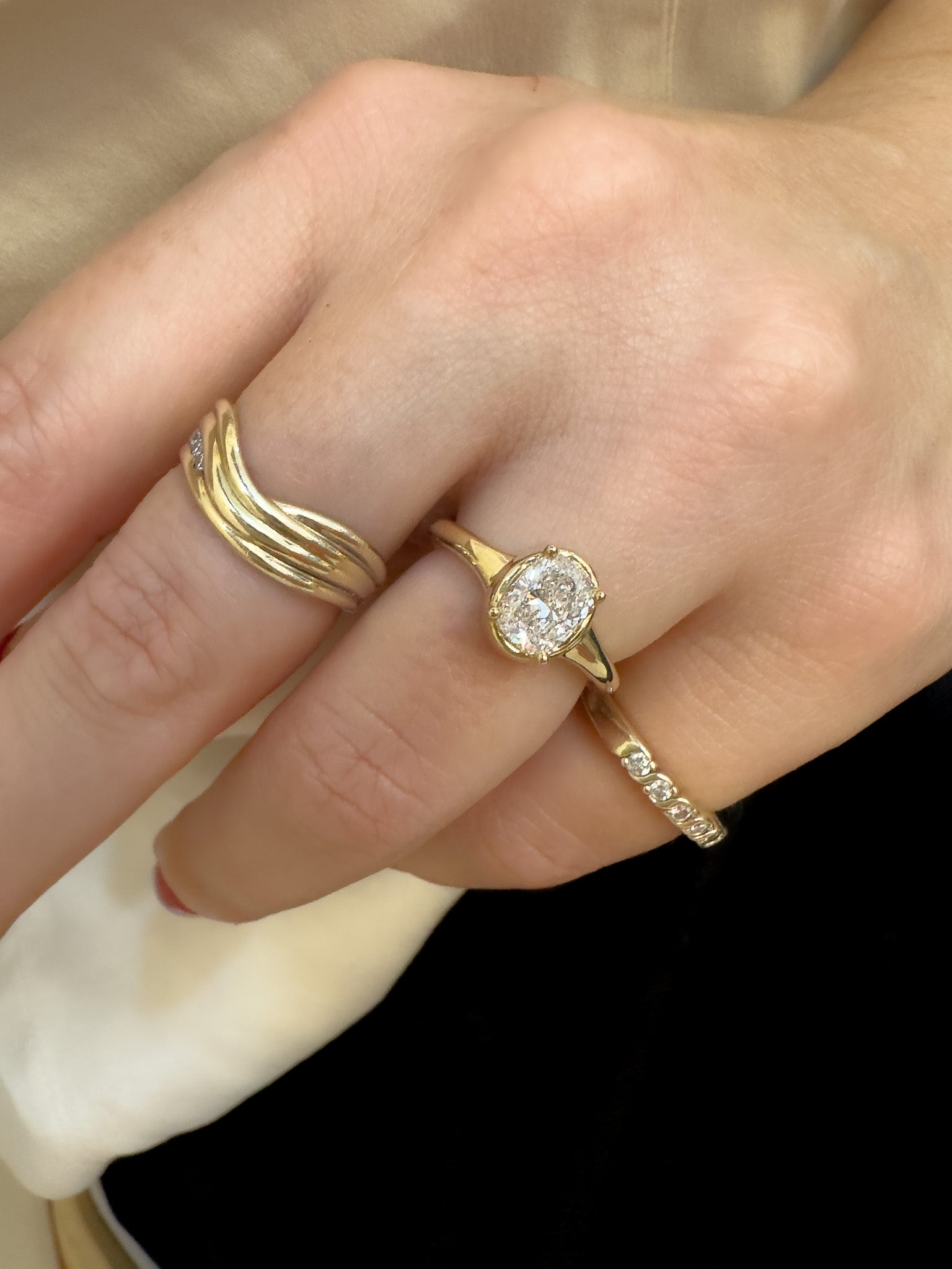 Hand wearing a gold ring with a diamond on a plain background