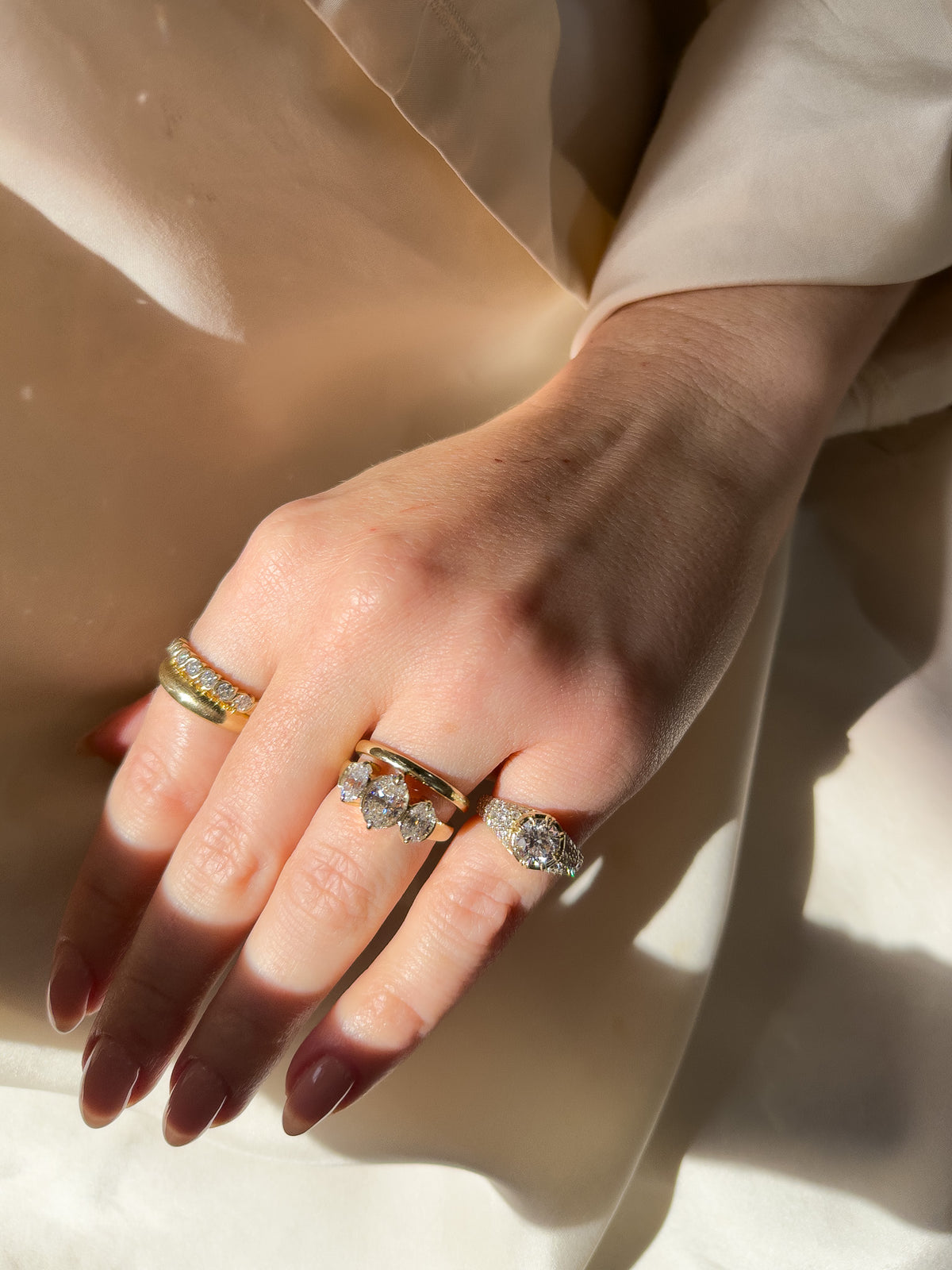 Gold ring collection of a trilogy engagement ring with oval diamonds, a narrow gold wedding ring and diamond signet ring. Gold and diamond Jewellery in South Africa