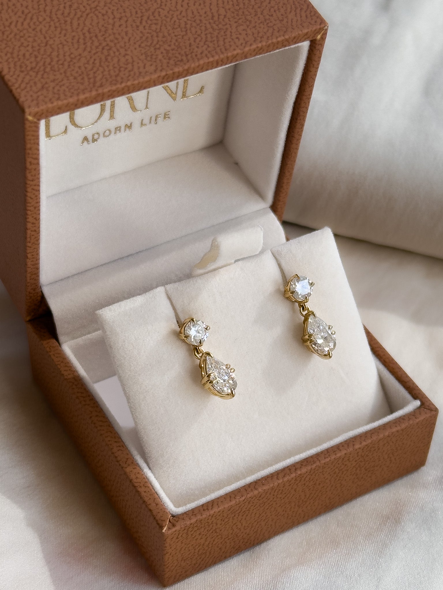Gold earrings with clear stones in a brown jewelry box