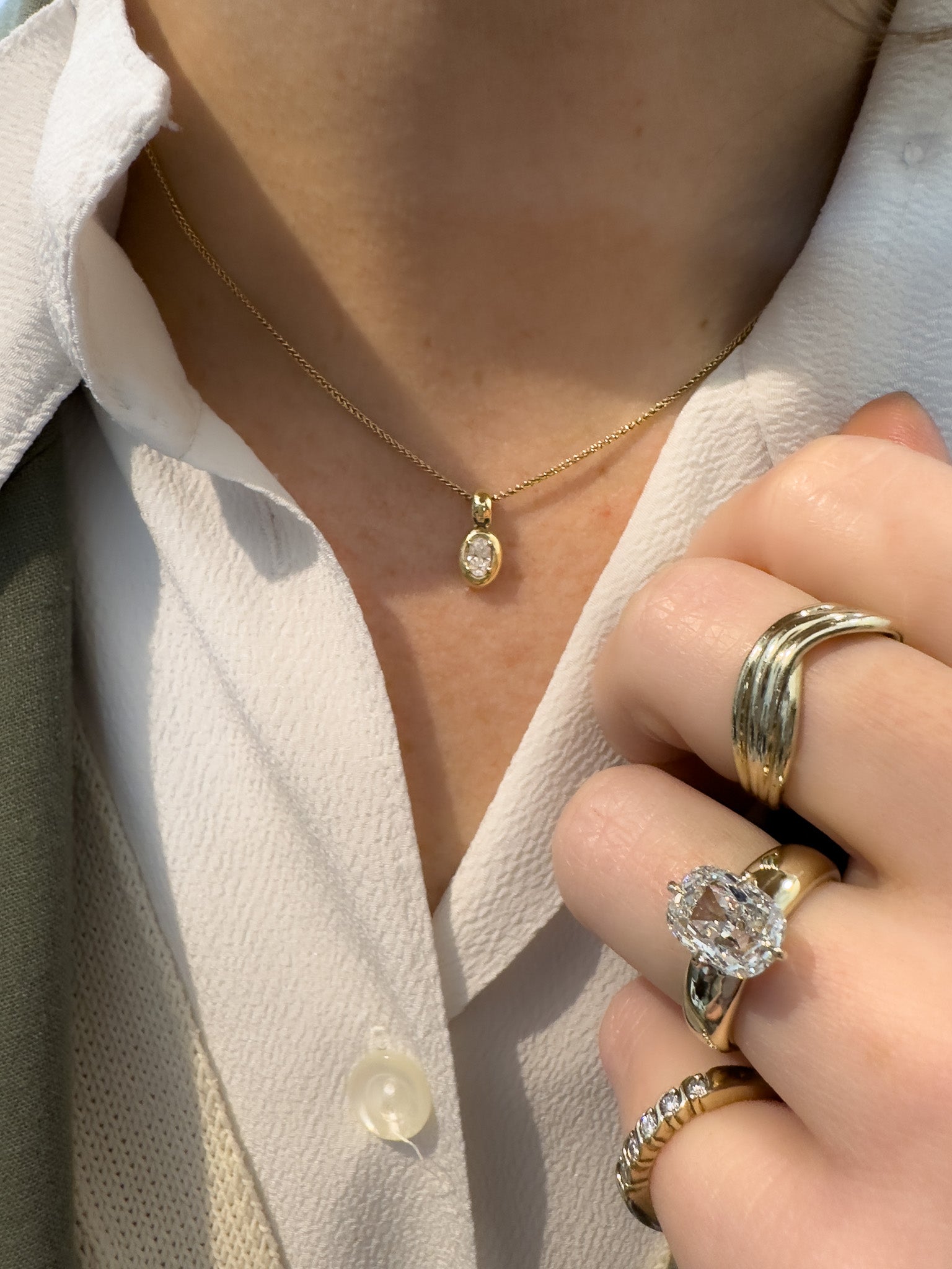 Close-up of a person wearing gold jewelry including a necklace and rings.