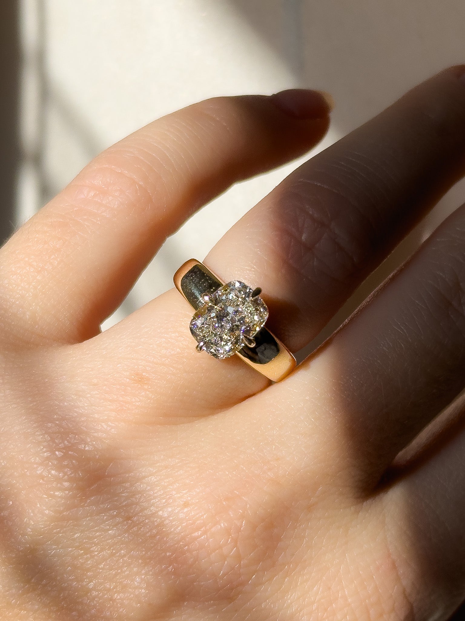 Gold ring with a diamond on a hand against a neutral background