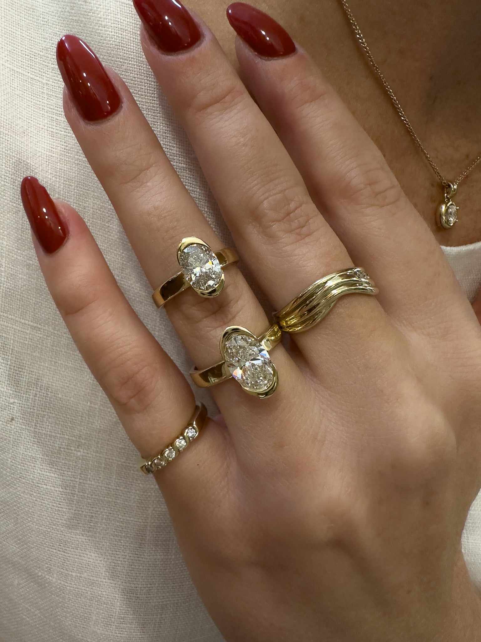 Hand wearing multiple gold rings with diamond accents on a neutral background