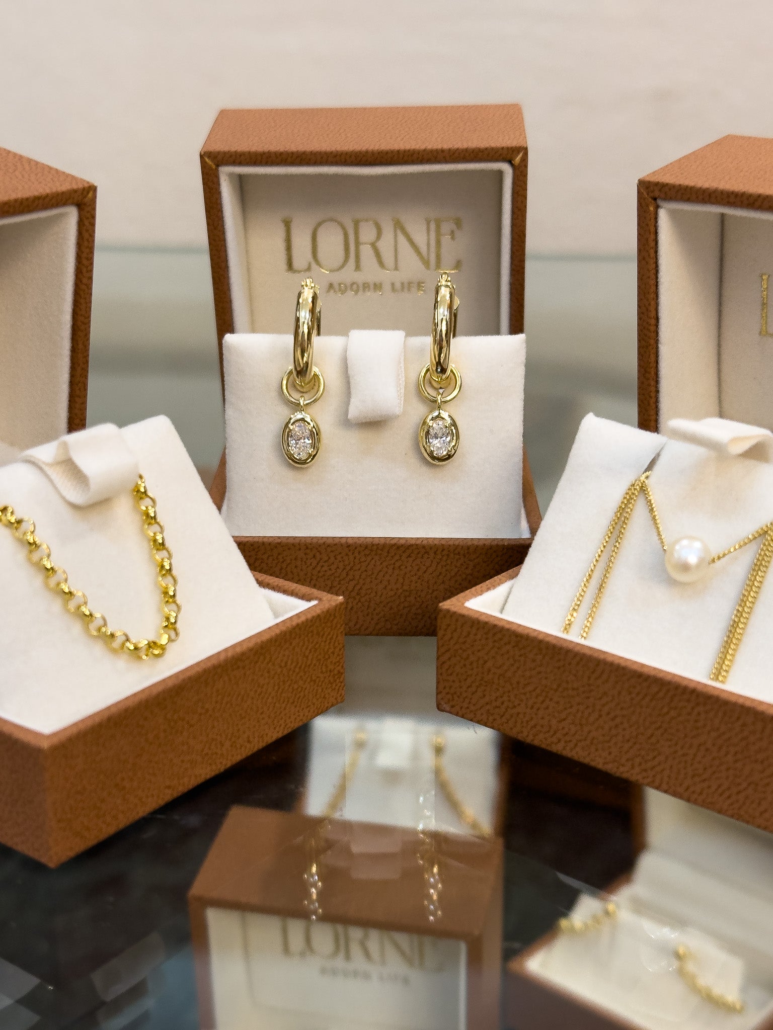 Gold jewelry set in LORNE boxes on a reflective surface