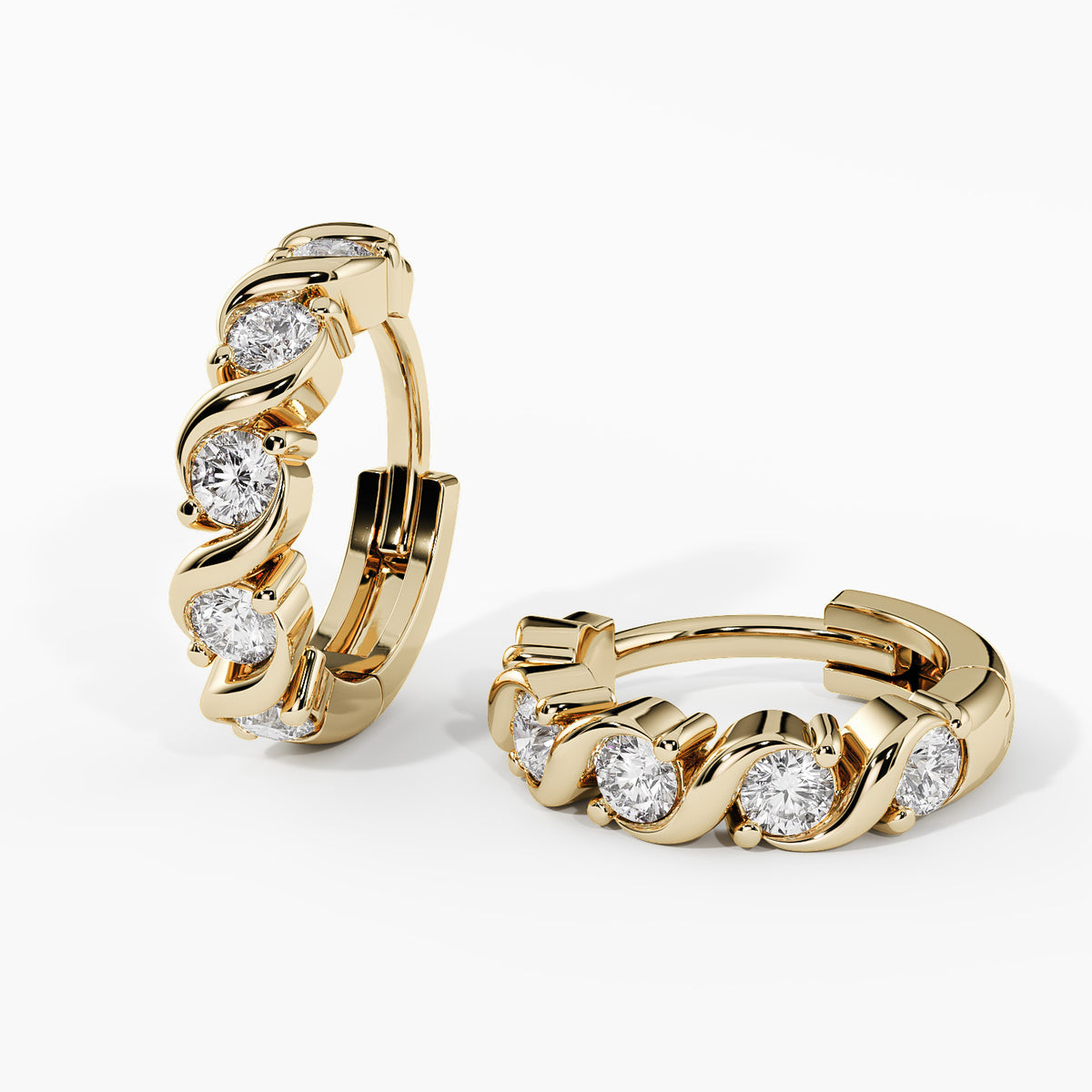 A pair of gold huggie hoop earrings with a wavy channel setting holding clear round-cut stones, shown on a clean white background.