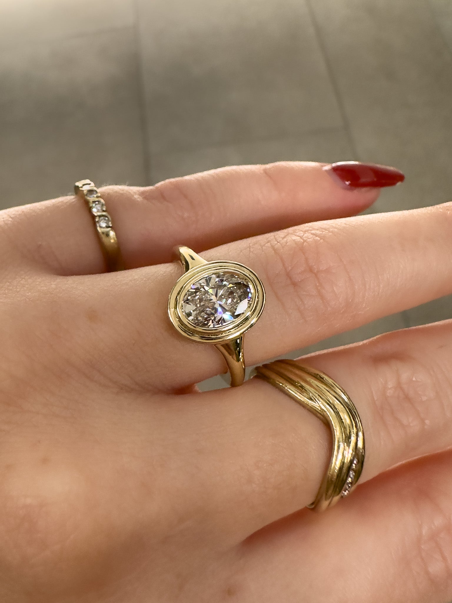 Gold ring with a large diamond on a hand against a neutral background