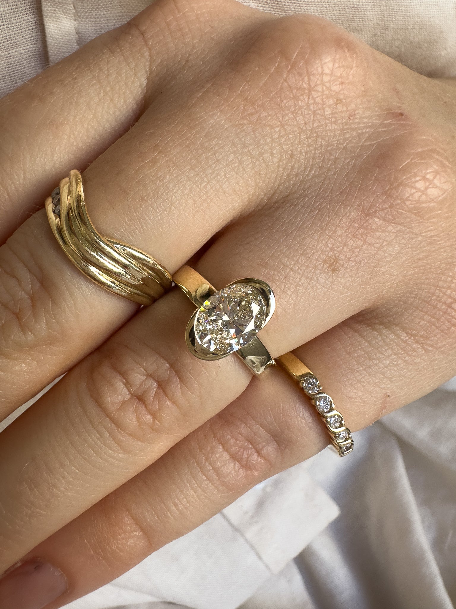 Close-up of a hand wearing three gold rings with different designs.