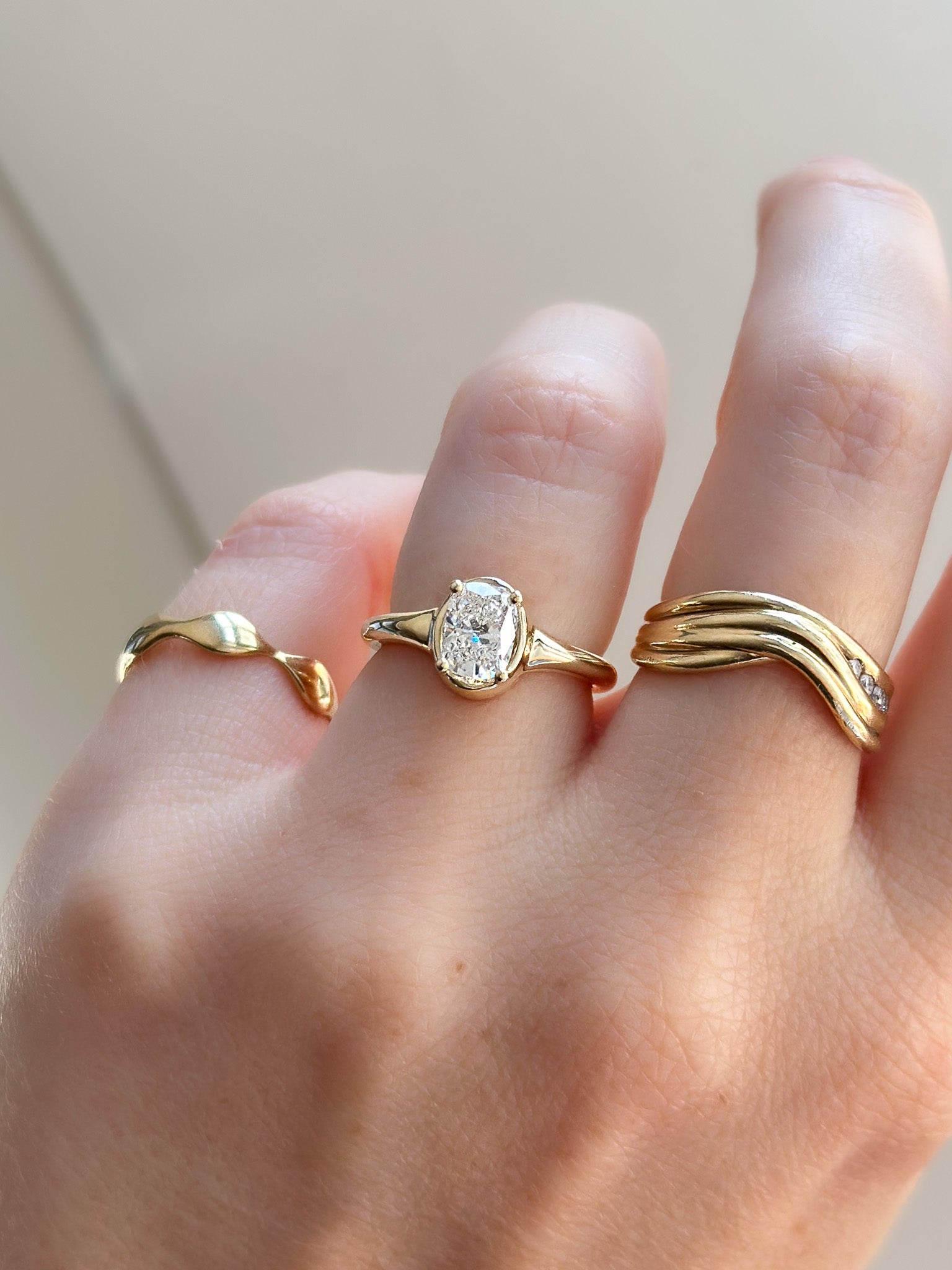 Gold ring with a diamond on a finger against a neutral background