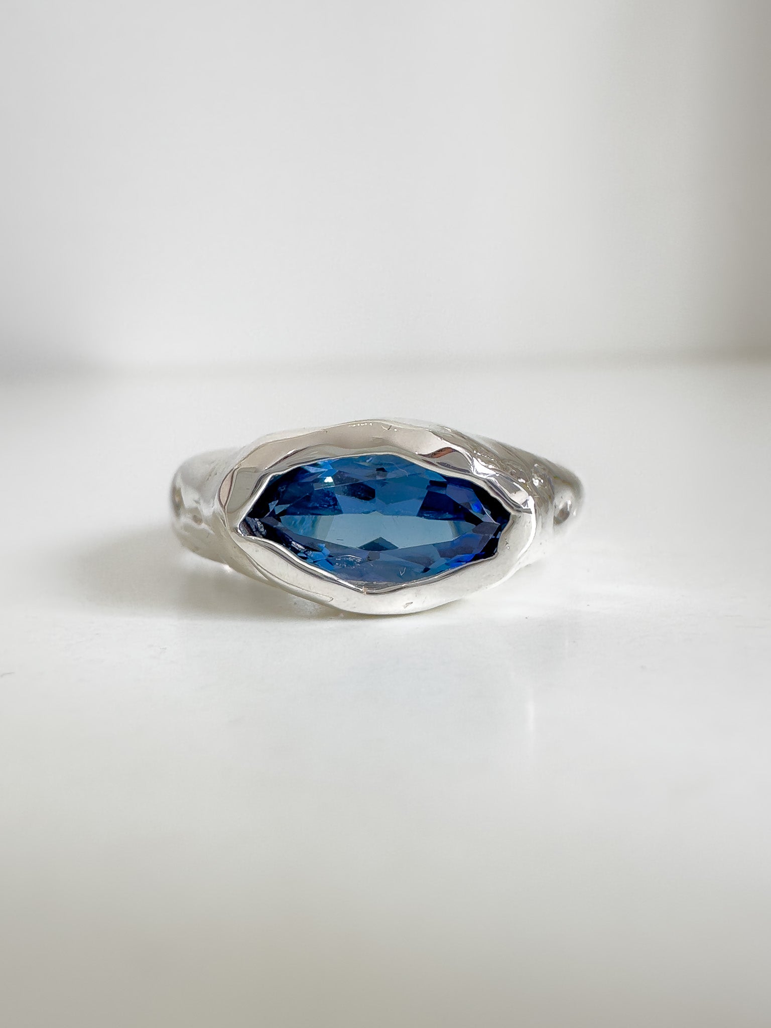 Silver ring with a blue gemstone on a white background