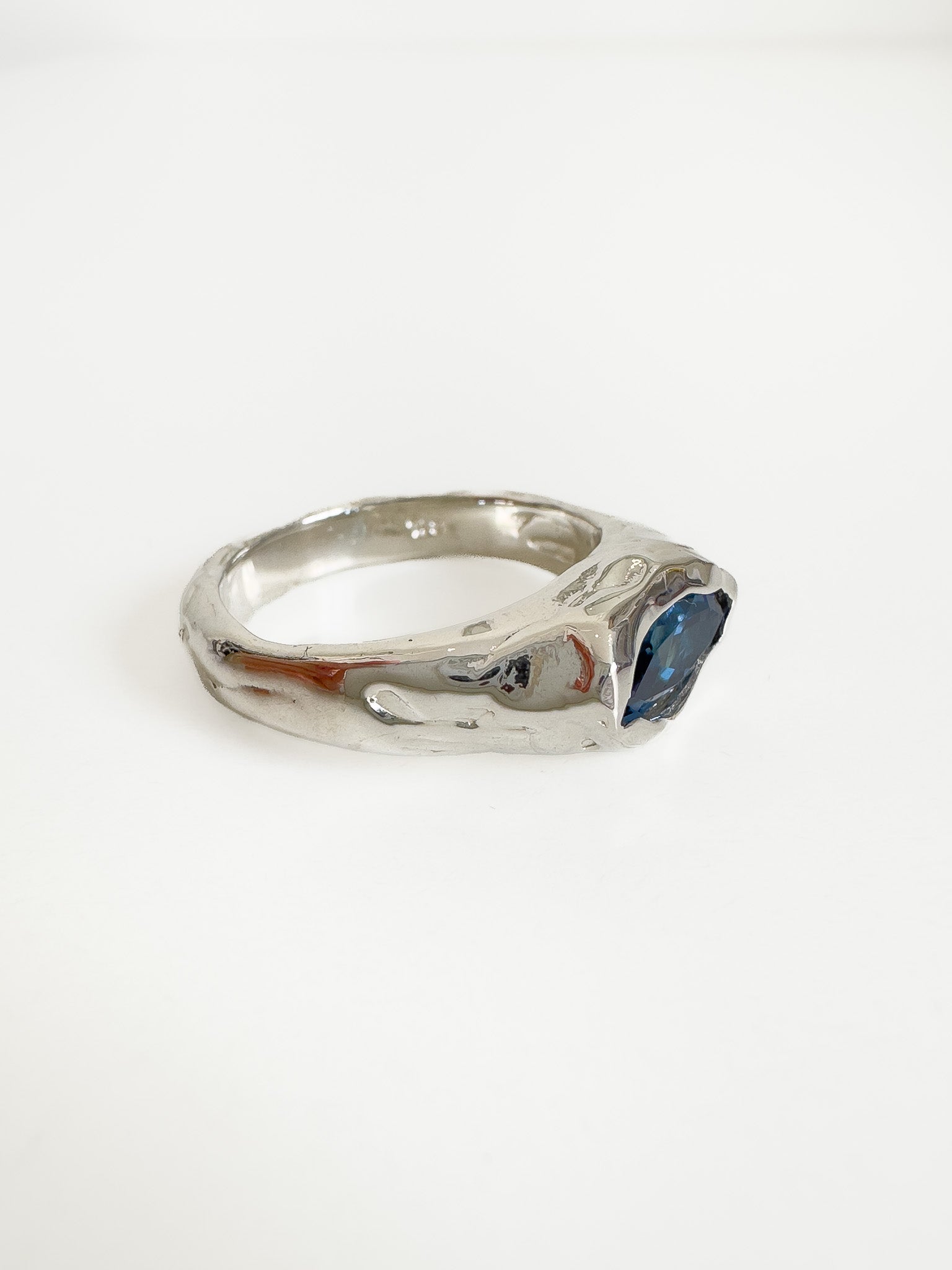 Silver ring with a blue gemstone on a white background